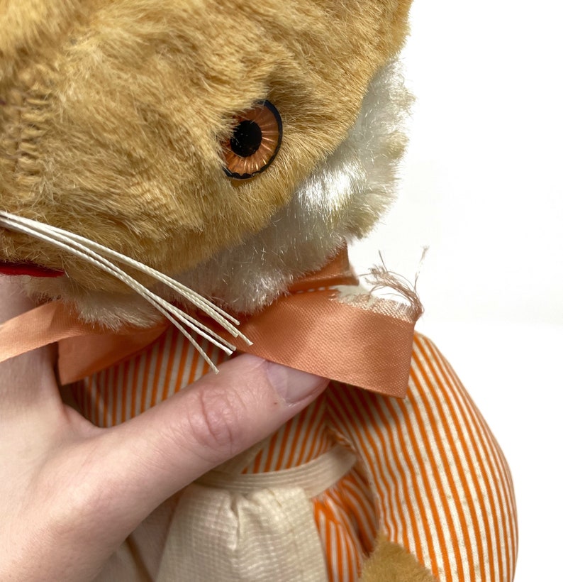 Op de afbeelding: Een vintage pluche vos met oranje-wit gestreept stof, een perzikkleurig lint om de nek en bruine ogen.