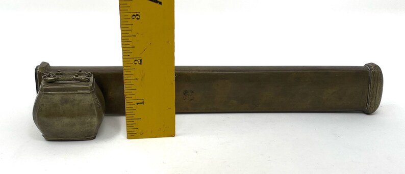May include: A brass box with a smaller brass box attached to it. The boxes are both rectangular and have a slightly rounded edge. The larger box is about 7 inches long.