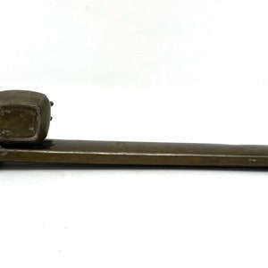 May include: A brown metal inkwell with a square base and a round top. The inkwell is attached to a long, rectangular metal base.