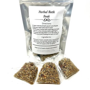 May include: A silver pouch with a white label that reads "Herbal Bath Soak". The label includes directions and ingredients for the bath soak. Three small white pouches filled with dried herbs are in front of the pouch.