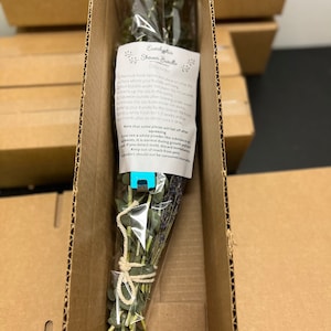 May include: A bundle of eucalyptus and lavender tied with twine in a clear plastic bag. The bundle is inside a cardboard box. The text on the label reads "Eucalyptus Shower Bundle Directions: Remove hook before placing on a dry surface where your bundle will hang. Run bundle under hot water for 10 seconds. Warm up the oils in the stems. Squeeze bundle after running under water. Hang your bundle by the loop on the hook. Enjoy the oils from inside the stems. Enjoy while fresh for 1-2 weeks and then throw away after as for or once it dries. Note that some pieces will fall off after you see a white powder-like substance on the leaves. It is normal during growth and not mold. If you detect mold, discard immediately. Keep out of reach from pets. Product should not be consumed internally."