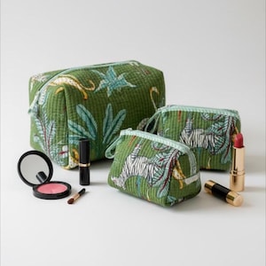 May include: Three green quilted cosmetic bags with a jungle print featuring tigers, leaves, and other foliage. Makeup items, including lipstick and blush, are arranged near the bags. The bags vary in size, with a large rectangular bag and two smaller zippered pouches.