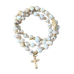May include: A triple-strand bracelet with white and gold beads and a gold cross charm.