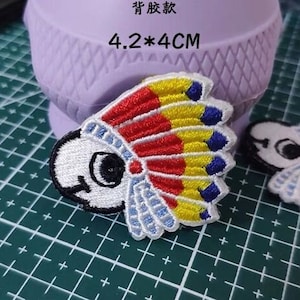 May include: Two embroidered iron-on patches featuring a cartoon bird wearing a colorful headdress. The patches are 4.2 by 4 centimeters. The text "背胶款" and "4.2*4CM" are visible in the image.