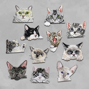 May include: Ten embroidered iron-on patches featuring different cat designs. The patches are in various colours, including black, white, grey, brown, and beige. The cats have different expressions, including playful, sleepy, and grumpy.