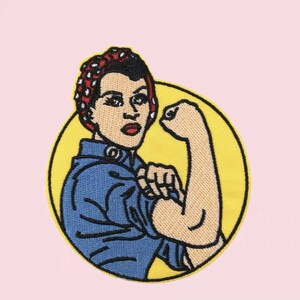May include: An embroidered iron-on patch featuring a woman with a red and white polka dot bandana, flexing her bicep. The woman is wearing a blue shirt and the background is yellow.