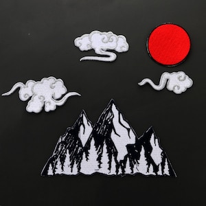 May include: White embroidered patches of mountains, clouds, and a red sun on a black background.