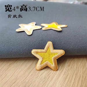 Puede incluir: Tres parches termoadhesivos en forma de estrella dorada. Las estrellas están bordeadas de oro y tienen un centro amarillo. El texto "宽4*高3.7CM  烫  服装" es visible en la imagen.