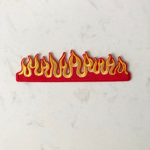 May include: Red and yellow embroidered flame patch. The patch is made of felt and has a red base with yellow flames.