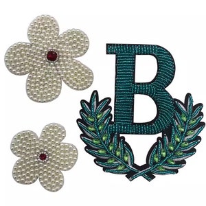 May include: Three embroidered patches, one with the letter "B" surrounded by green leaves, and two white flower patches with red centers.