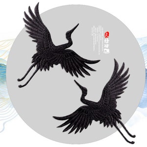 May include: Two black embroidered crane appliques. The cranes are in flight with their wings spread. The appliques are perfect for adding a touch of Asian-inspired style to clothing, bags, or home decor.