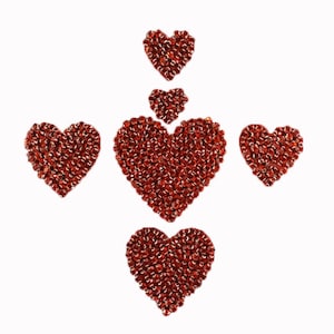 May include: Five red heart-shaped decorations made of small red beads. The hearts are arranged in a vertical line, with the largest heart at the bottom and the smallest heart at the top.