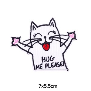 May include: White embroidered iron-on patch of a cartoon cat with a red tongue sticking out. The cat has pink paws and says "Hug Me Please!" in black text. The patch is 7x5.5 cm.