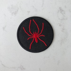 May include: Black embroidered patch with a red spider design.