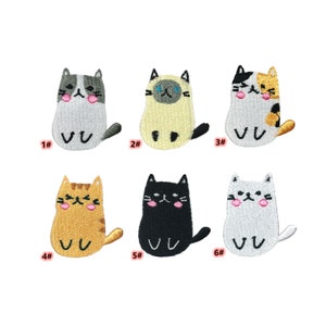May include: A collection of six embroidered cat patches in various colors. Each patch features a cartoon cat design with different expressions and markings. The patches are numbered 1 through 6.