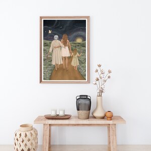 K&ouml;nnte beinhalten: Eine gerahmte Illustration von drei Generationen von Frauen, die auf einem Weg unter einem sternenklaren Nachthimmel gehen. Die Frauen halten sich an den H&auml;nden und gehen auf ein helles Licht in der Ferne zu. Der Weg ist mit lila Blumen ges&auml;umt.