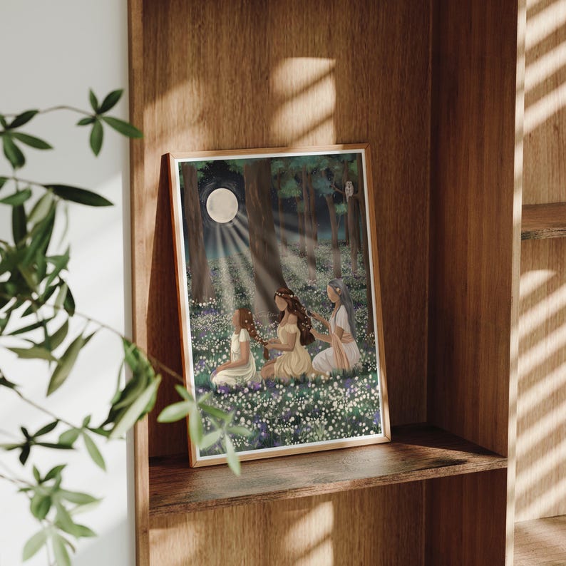 May include: A framed art print depicting three figures in a moonlit forest clearing. The artwork features a full moon, rays of light, and a field of white flowers. The figures are dressed in flowing gowns, with long hair, and are seated in the flowers.