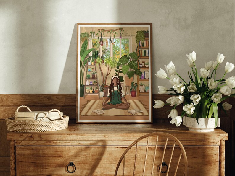 May include: A framed illustration of a woman meditating in a room filled with plants. The woman is wearing a green shirt and has long brown hair. The room has a window with a view of trees and a bookshelf filled with books.