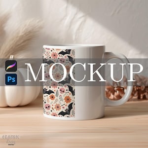 May include: White ceramic mug with a wraparound design featuring bats, skulls, and flowers in black, pink, and orange. The word "MOCKUP" is displayed across the center of the mug. The mug is on a wooden surface.