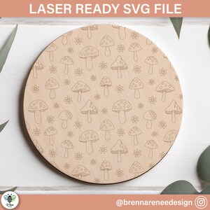 Könnte beinhalten: Ein runder Holz-Untersetzer mit einem Laser-geschnittenen Design aus weißen Pilzen und Blumen. Der Untersetzer ist perfekt, um Ihrem Zuhause einen Hauch von Verspieltheit zu verleihen.