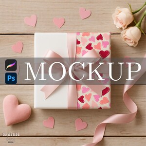 May include: A white gift box with a pink ribbon and bow, decorated with pink and red heart-patterned wrapping paper. Pink heart-shaped cutouts and two roses are scattered around the box on a wooden surface. The word "MOCKUP" is displayed across the center.