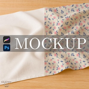 May include: A folded fabric mockup with a floral pattern and solid white sections. The floral design features pink flowers and blue leaves on a cream background. The word "MOCKUP" is displayed in large white letters.