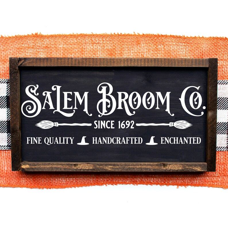 Peut inclure: Une enseigne en bois noir avec des lettres blanches qui disent "Salem Broom Co. Since 1692" avec un balai et un chapeau de sorci&egrave;re en graphique de chaque c&ocirc;t&eacute; du texte. L'enseigne dit &eacute;galement "Fine Quality", "Handcrafted", et "Enchanted" avec un chapeau de sorci&egrave;re en graphique entre chaque mot.