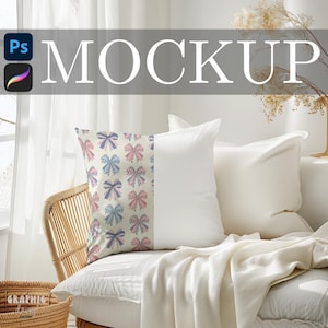 May include: A white pillow with a pattern of pink, blue, and purple bows. The pillow is on a white couch with a white blanket. The word "MOCKUP" is displayed in large white letters above the pillows.