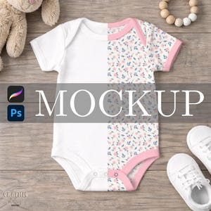 May include: White baby onesie with a floral pattern on one side, accented with pink trim. The word "MOCKUP" is displayed across the center. A pair of white baby shoes are visible.