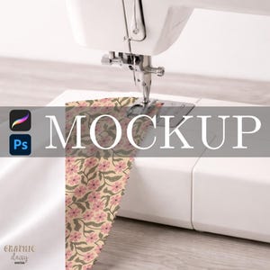 May include: A white sewing machine with a needle piercing a floral patterned fabric. The fabric features pink flowers and green leaves on a beige background. The word "MOCKUP" is overlaid on the image.