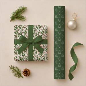 Pu&ograve; includere: Un regalo confezionato con un fiocco verde, carta da regalo a motivi di agrifoglio e un rotolo di carta da regalo verde con alberi di Natale bianchi. Un ornamento argentato, nastro verde, rametti di pino e una pigna completano il tema delle feste.