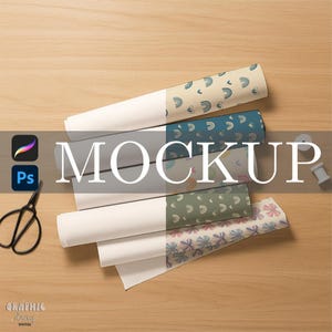 May include: A mockup image featuring rolls of patterned paper in various designs, including rainbows and bows. The word "MOCKUP" is prominently displayed across the image. A pair of black scissors and design software icons are also visible.