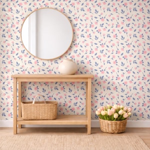 May include: A light wood console table with a woven basket on the lower shelf. A round mirror hangs above the table. The wall is covered in a floral pattern with pink flowers and blue leaves. A vase sits on the table.