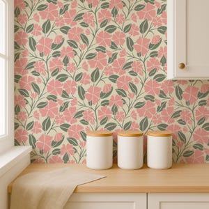 Puede incluir: Papel pintado floral con un patr&oacute;n repetitivo de flores rosas y hojas grises sobre un fondo crema. Tres botes de cer&aacute;mica blanca con tapas de madera sobre una encimera de madera. Dise&ntilde;o decorativo.