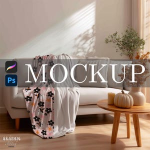 May include: A cozy living room scene featuring a white sofa with gray pillows and blankets. A patterned blanket with black flowers and orange stars is draped over the sofa. A small wooden table holds a pumpkin, candles, and vases. The word "MOCKUP" is displayed.
