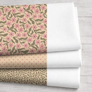 May include: Three fabric swatches with floral and leaf patterns in pink, tan, and brown, alongside folded white fabric. The top swatch features pink flowers and gray leaves on a tan background. The other two swatches have smaller floral and leaf designs.