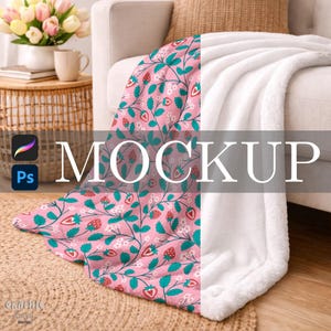 Puede incluir: Una manta sobre un sofá, con un diseño de fresas y flores sobre un fondo rosa. La otra mitad de la manta es de un material suave y blanco. La palabra "MOCKUP" está superpuesta en la manta.