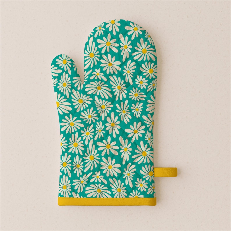 Puede incluir: Un guante de cocina turquesa con un estampado de margaritas blancas con centros amarillos. Tiene un ribete amarillo y un lazo para colgar. Un complemento alegre y brillante para cualquier cocina, medidas en cm.