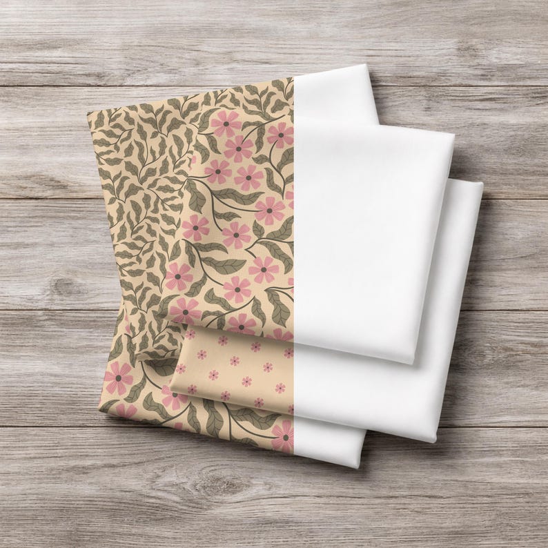 May include: A stack of folded fabric items. The left side features floral patterns with pink flowers and green leaves on a beige background. The right side shows plain white fabric. The items are stacked on a wooden surface.