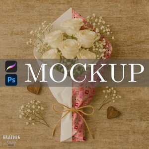 May include: A bouquet of white roses wrapped in pink and white paper, tied with twine. The bouquet is decorated with baby's breath and wooden heart accents. The word "MOCKUP" is displayed in large white letters.