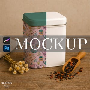 May include: A rectangular tea tin with a teal and white lid, and a patterned side featuring teapots, honey pots, and lemons. The word "MOCKUP" is displayed in large white letters. A wooden scoop holds tea leaves, and a small bouquet of dried flowers sits nearby.