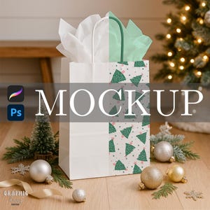 Könnte beinhalten: Weiße Geschenktüte mit einem Weihnachtsmuster und dem Wort "MOCKUP" in großen weißen Buchstaben. Die Tüte ist mit weißem Seidenpapier gefüllt und hat einen grünen Griff. Weihnachtsornamente und ein kleiner Baum sind im Vordergrund.