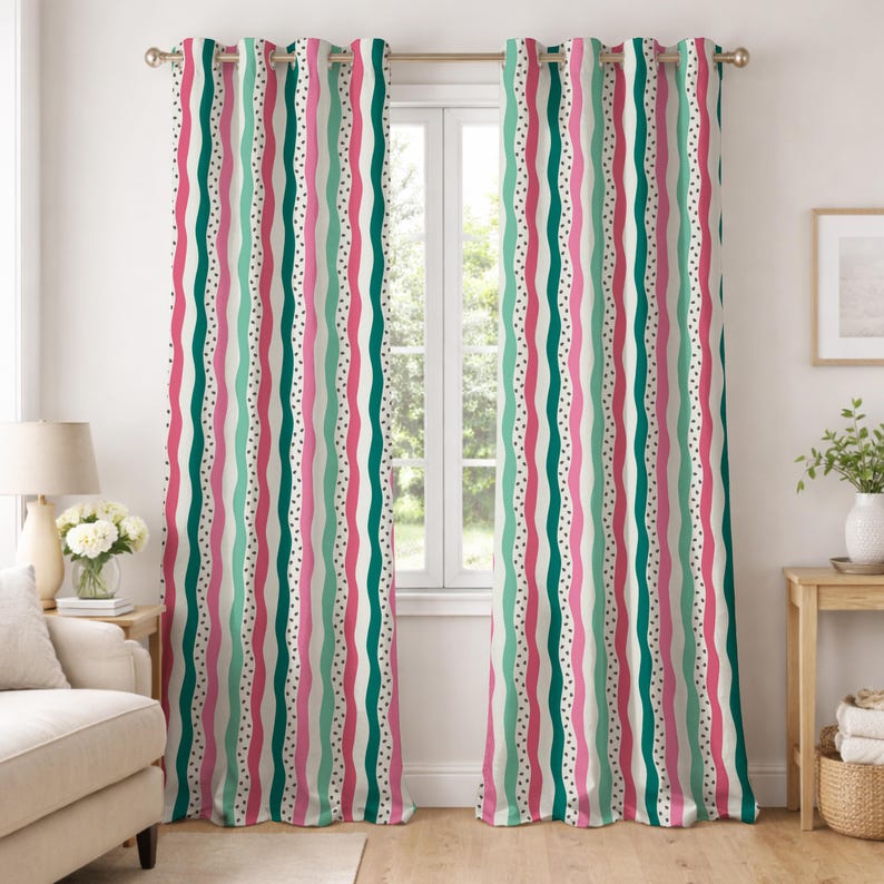 Op de afbeelding: Een paar kleurrijke, bedrukte gordijnen. Het ontwerp heeft verticale strepen in roze, teal en wit, met een stippenpatroon. De gordijnen hangen aan een gouden stang voor een raam en voegen een decoratief tintje toe aan de kamer.