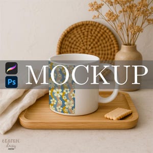 May include: A white ceramic mug with a floral design in blue, yellow, and peach tones. The mug is on a wooden tray with a biscuit. The word "MOCKUP" is displayed across the image.