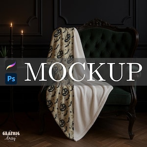 Puede incluir: Una manta con temática de Halloween sobre un sillón verde. La manta presenta un patrón de calabazas negras, murciélagos y estrellas sobre un fondo beige, con un lado suave de color crema. La palabra "MOCKUP" se muestra.