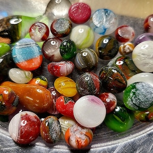 May include: A collection of colorful glass marbles in a variety of patterns and colors, including red, green, blue, yellow, and white.