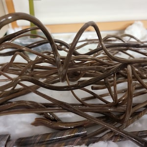 May include: A close-up of a pile of brown, flexible, twisted, and curled plastic tubes. The tubes are arranged in a random pattern and appear to be made of a soft, pliable material.