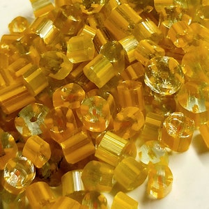 Puede incluir: Primer plano de un montón de caramelos duros amarillos y transparentes. Los caramelos tienen forma de pequeños cilindros y tienen un aspecto brillante y translúcido.