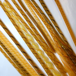 May include: A collection of glass rods with a variety of swirling patterns in shades of yellow, orange, and brown.