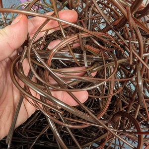 Puede incluir: Primer plano de un montón de alambre de plástico marrón. El alambre está enredado y retorcido.